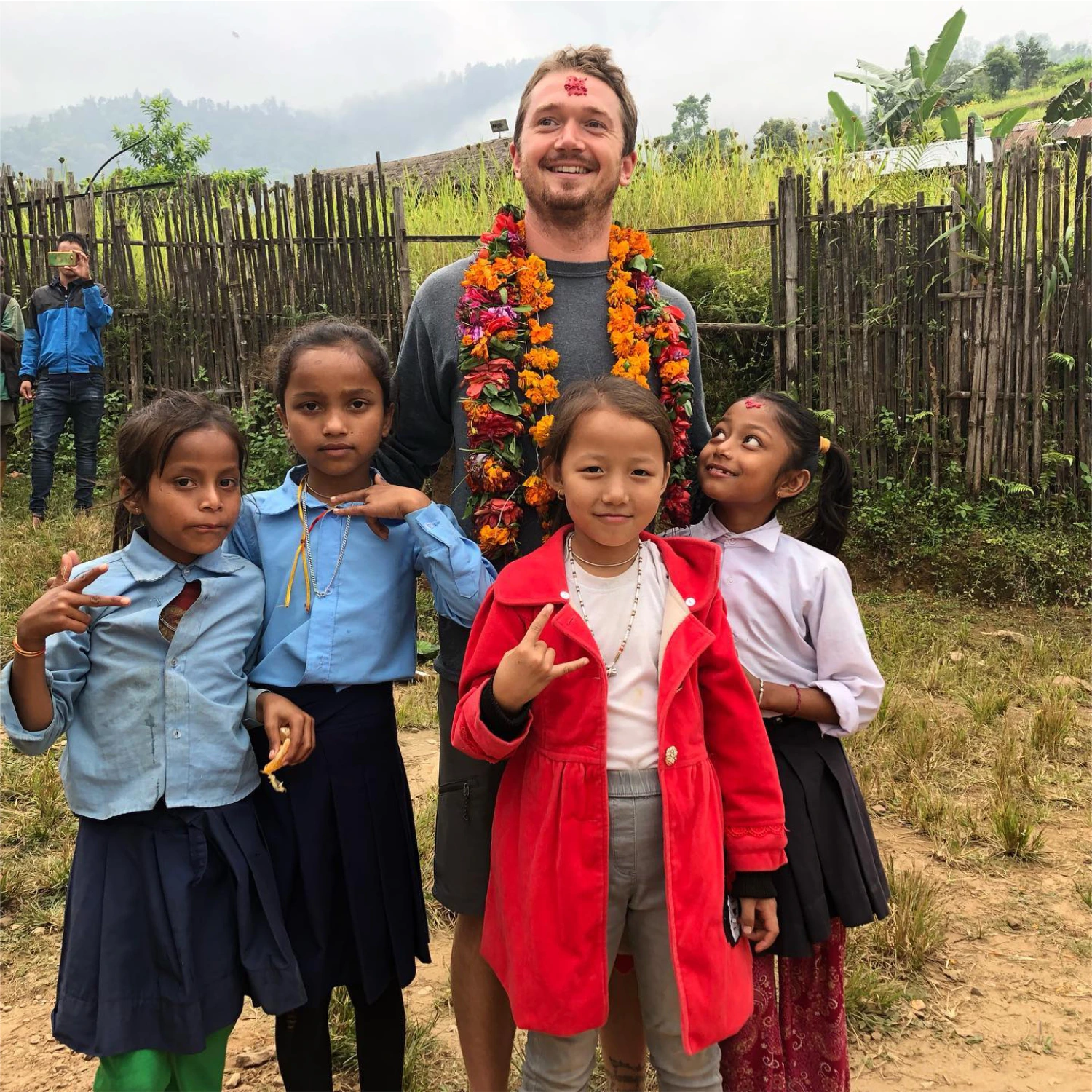 Kyle Sawyer standing with Nepalese school children